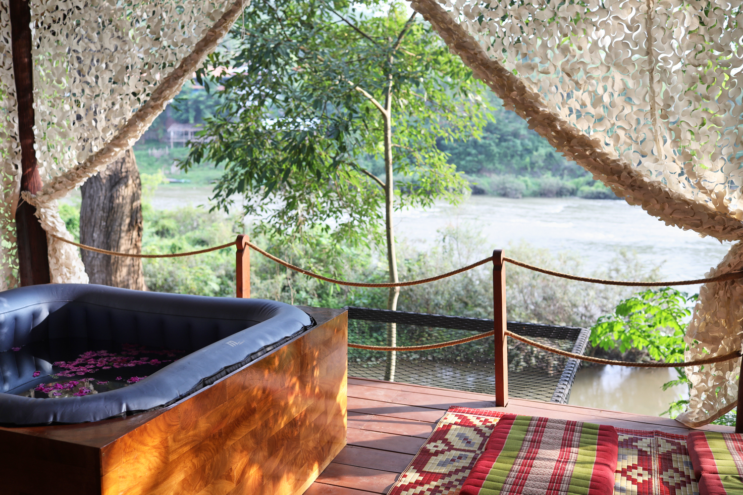 A hot tub on a deck overlooking the Luang Prabang river.