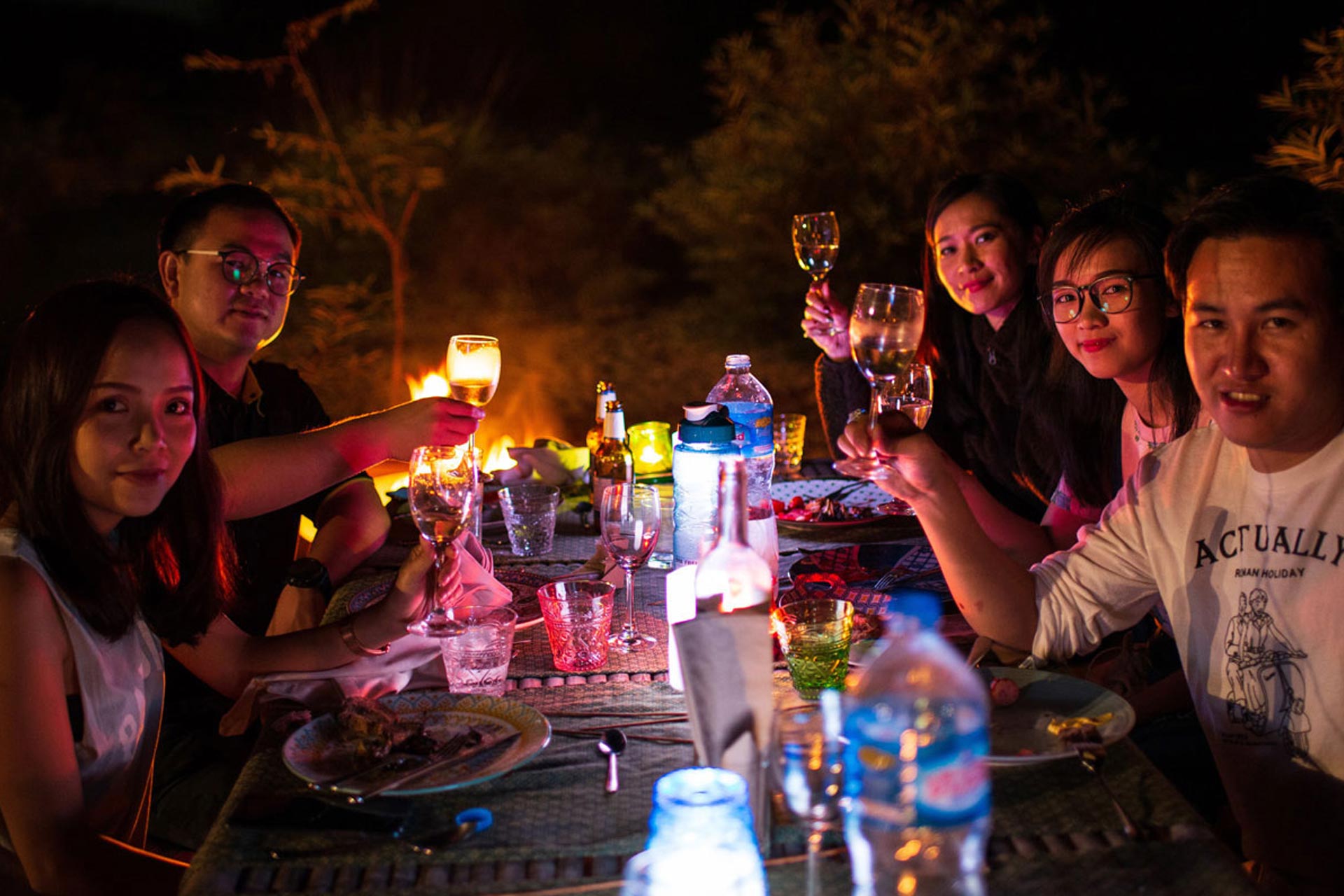 A group of people sitting around a table at night.