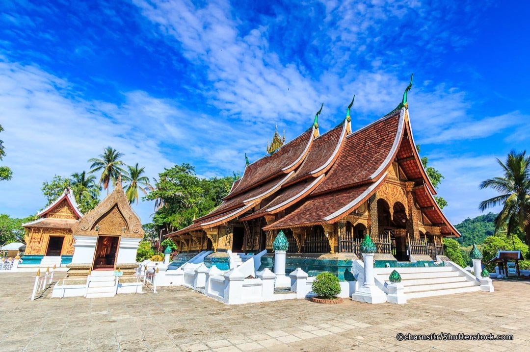 A Buddhist temple in Luang Prabang, Thailand with a blue sky in the background.