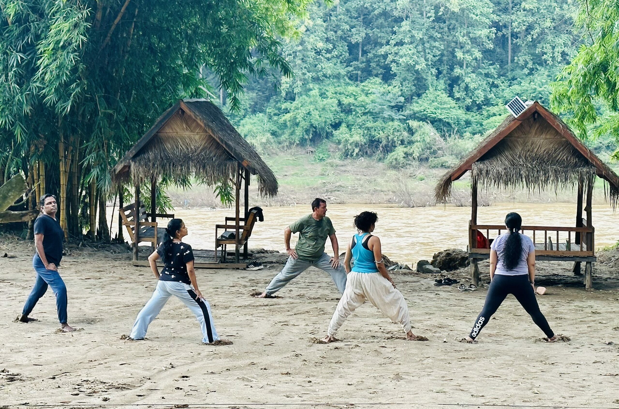 Multiple people doing Qi Gong with their feet in the sand