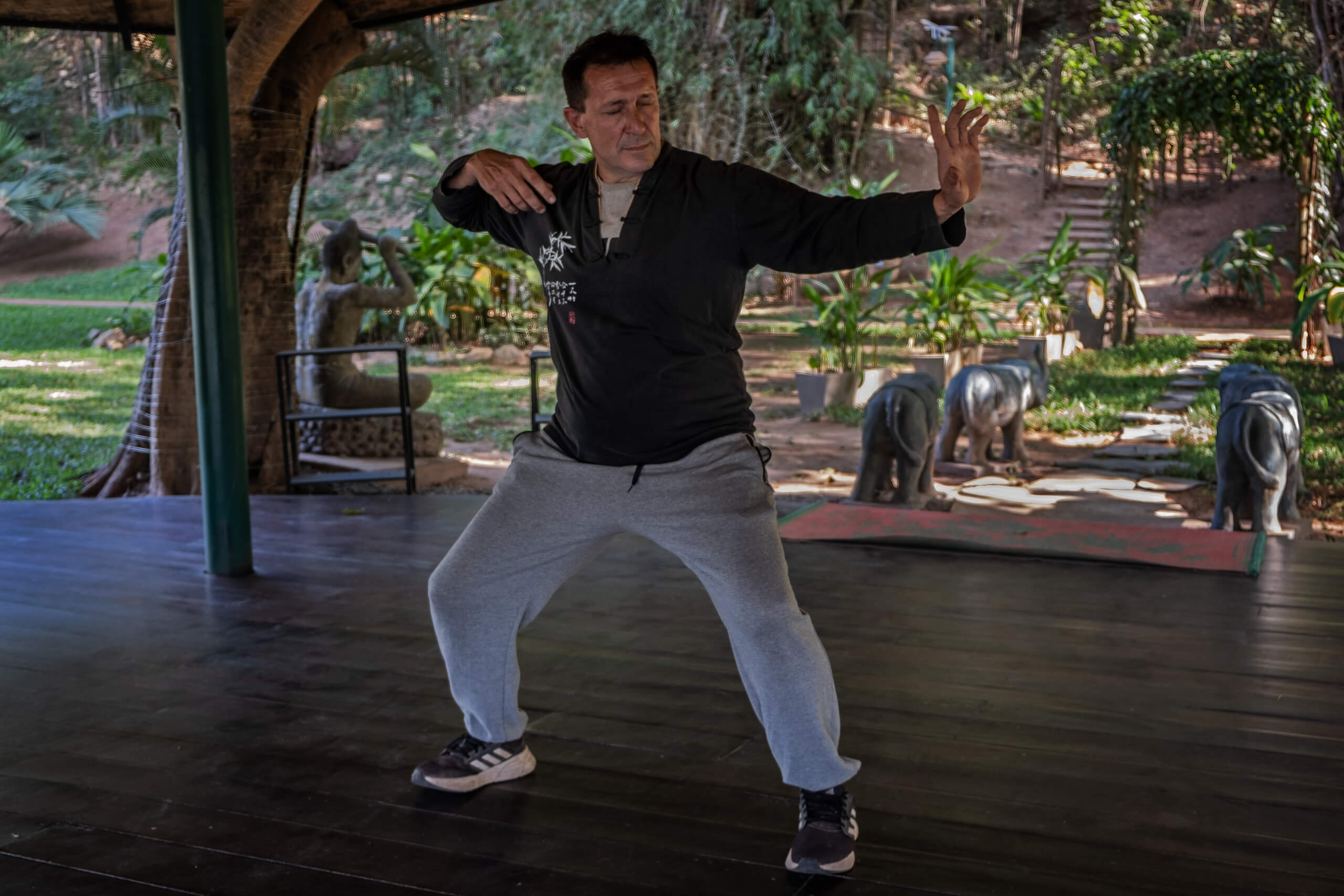 Man practicing qi gong on a wooden deck, cultivating balance and energy flow.