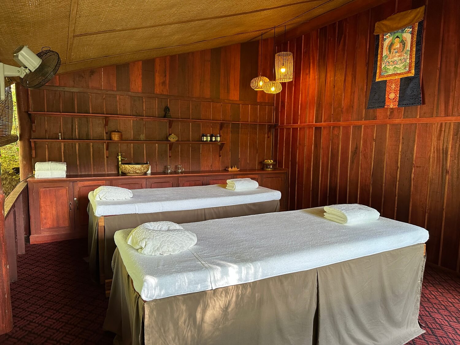 Two massage beds in a room with wood paneling in Luang Prabang.