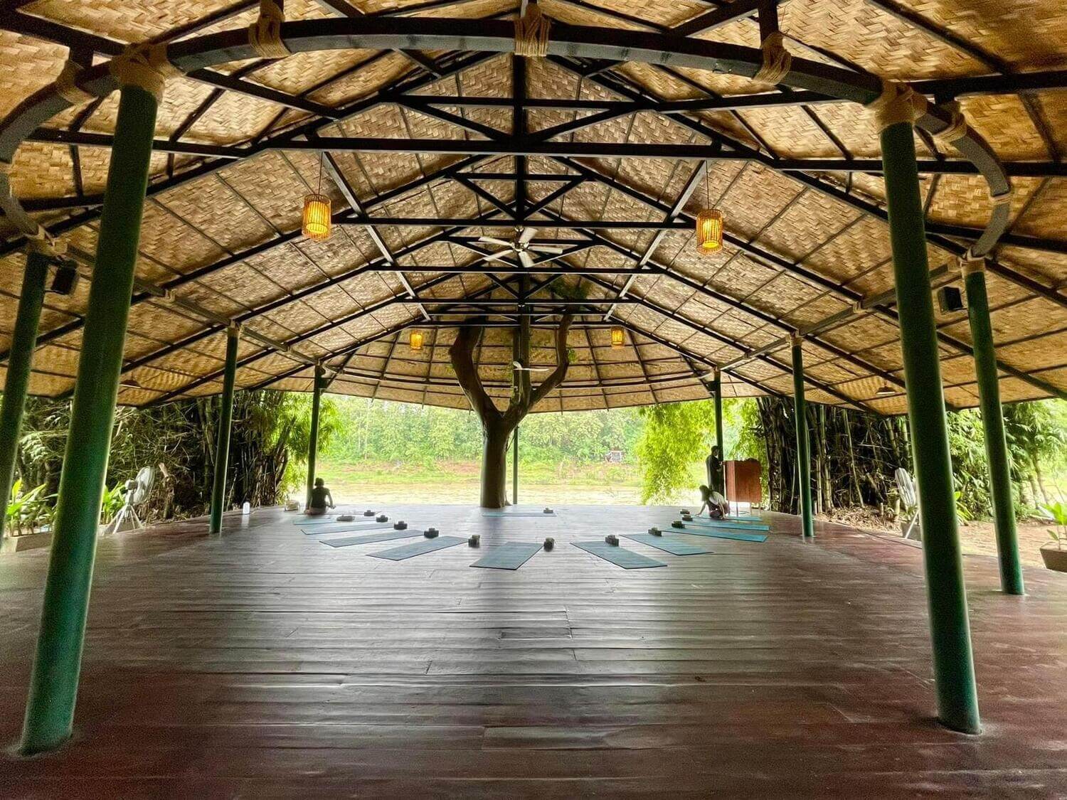 In the enchanting city of Luang Prabang, discover a tranquil yoga room adorned with a beautiful wooden floor, where you can find solace in your practice amidst the calming presence of