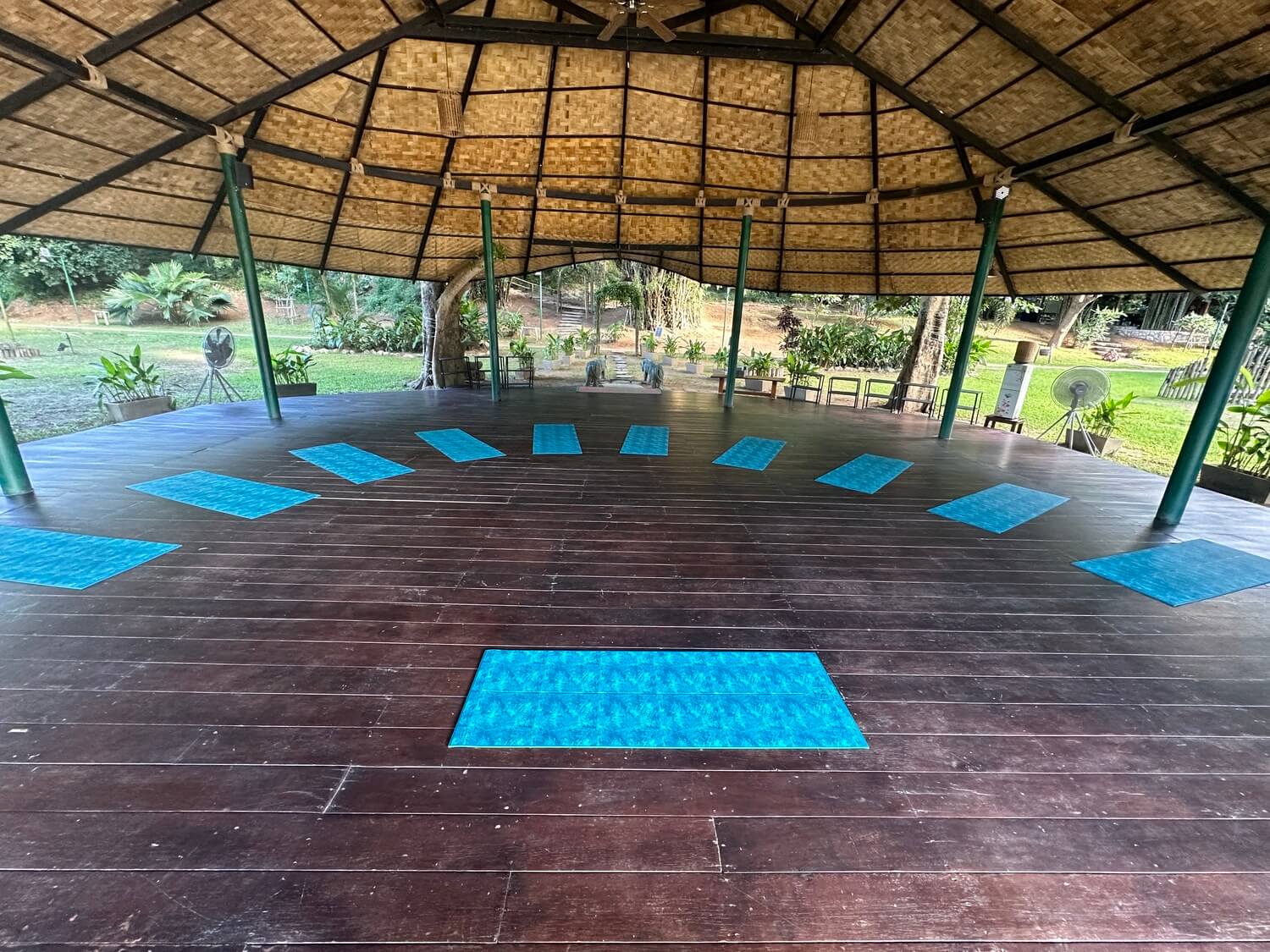 Yoga mats on a wooden floor under a thatched roof in Luang Prabang.