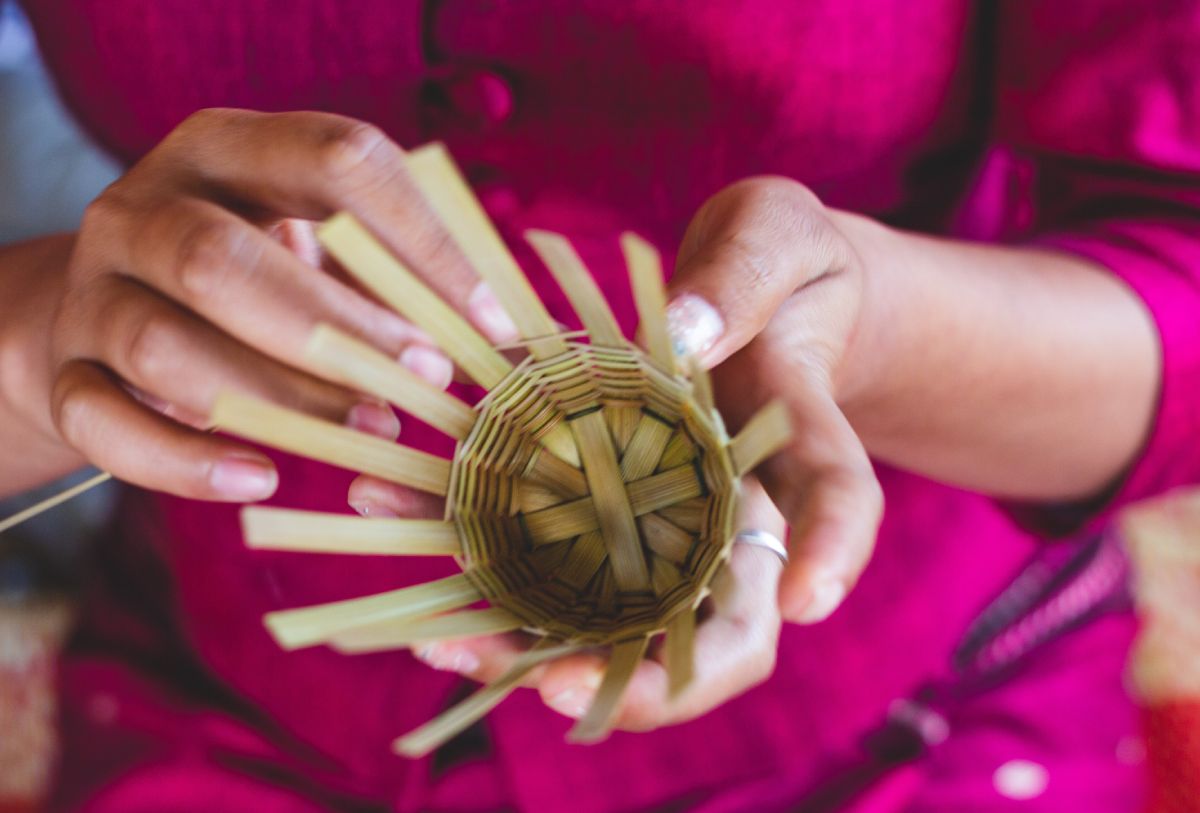 A woman is practicing bamboo weaving to create a basket.