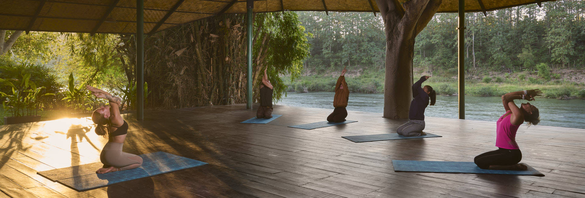 A group of people practicing yoga on a Luang Prabang wooden deck.