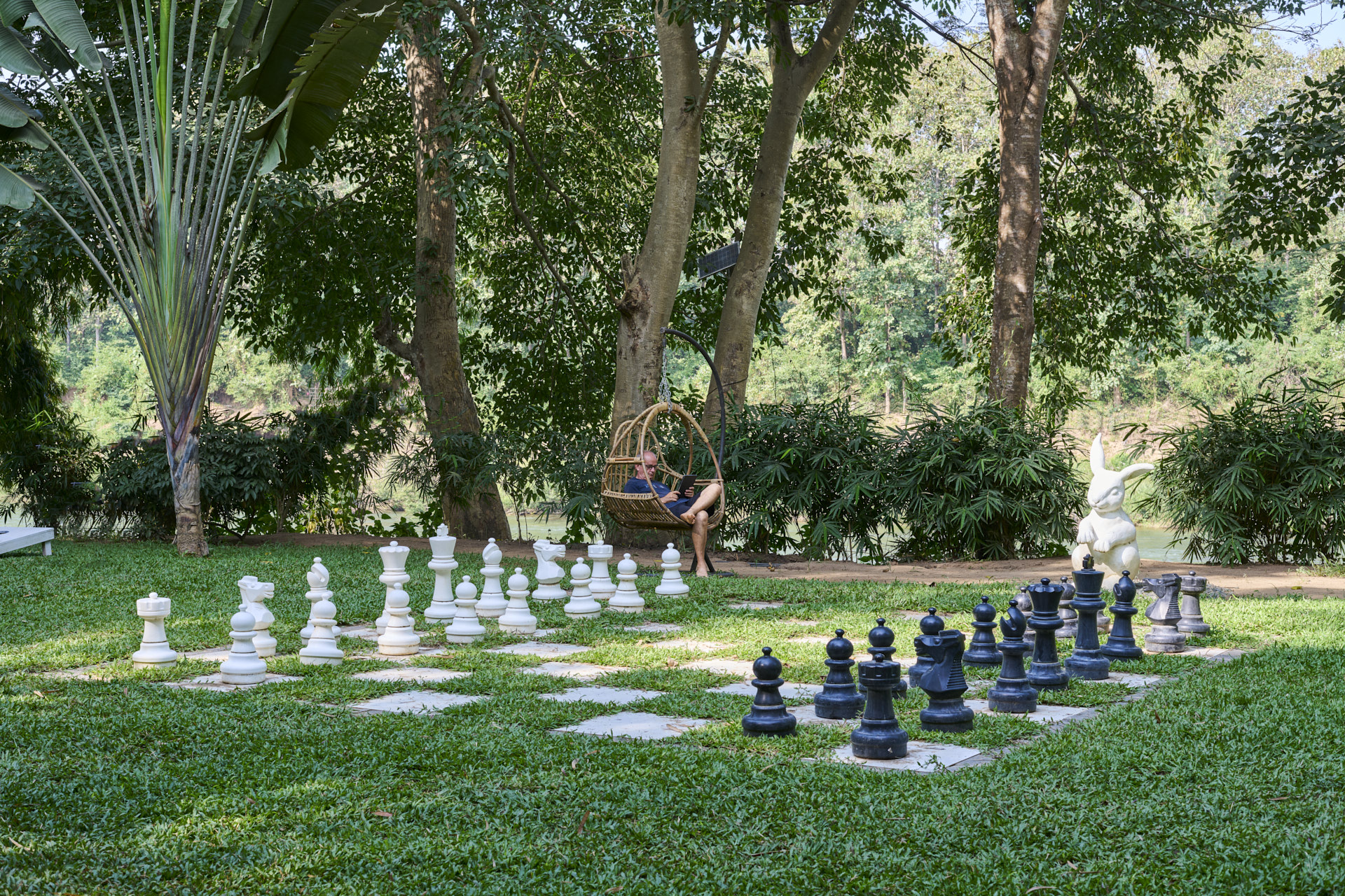 A person sitting in a chair next to a chess board, enjoying the peaceful ambiance of Luang Prabang.