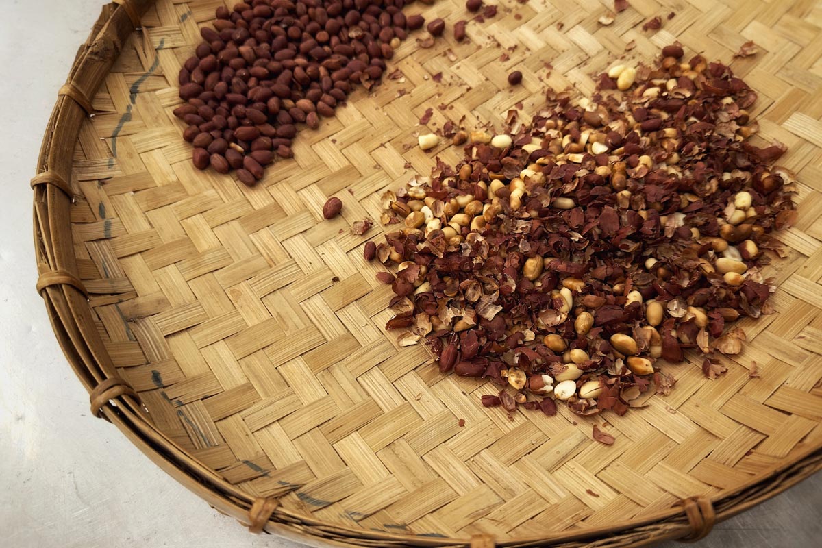 A wicker basket filled with seeds and nuts sits on a farm table.