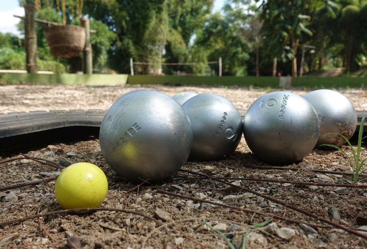 A group of balls on the ground in a playground, with a yellow ball in the middle.