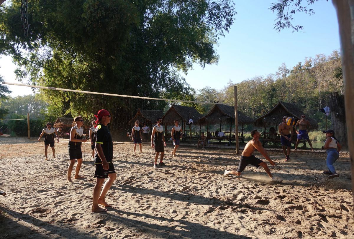 A group of people enjoying a game of volleyball on the sand at an outdoor playground.