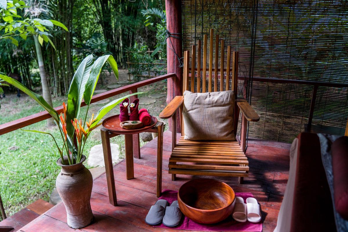 A wooden chair on a wooden deck with a potted plant, promoting wellbeing.