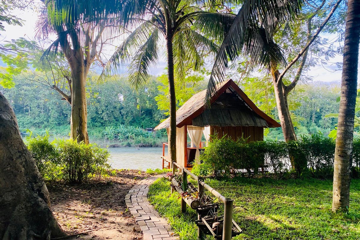 A serene small hut next to a calming river in Thailand, offering a tranquil space for wellbeing.