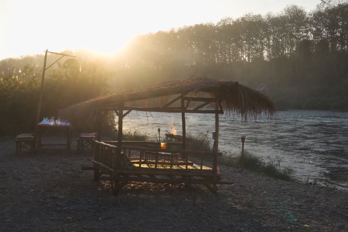 A table and chairs on the shore of a river, offering a serene spot to relax and recharge.