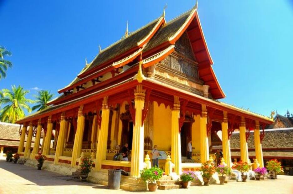 Wat Si Saket, a temple in Laos, stands tall with its majestic pillars against the backdrop of a serene blue sky.