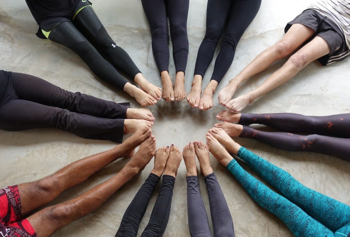 A group of people practicing yoga, standing in a circle with their feet together.