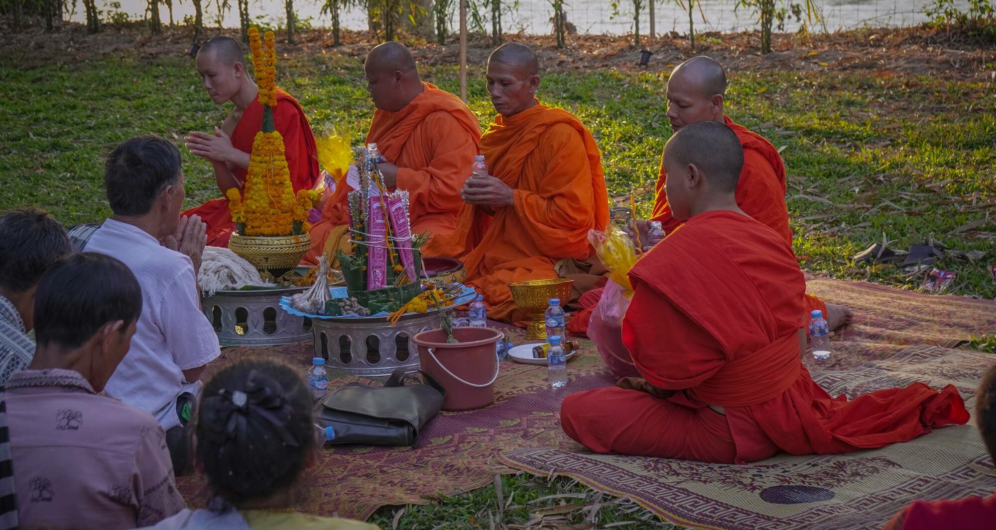 A group of monks sitting around a table in front of the Luang Prabang river.