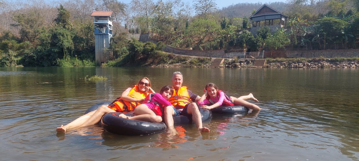 A group of people sitting on inflatable tubes in the Luang Prabang river.