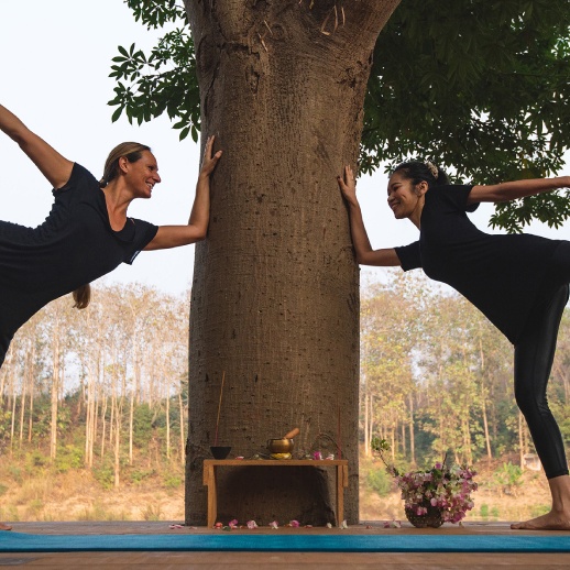 Two women in black standing next to a tree in Luang Prabang.