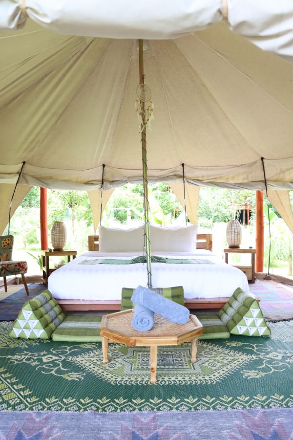 A bed and table with a rug in a glamping tent in Luang Prabang.