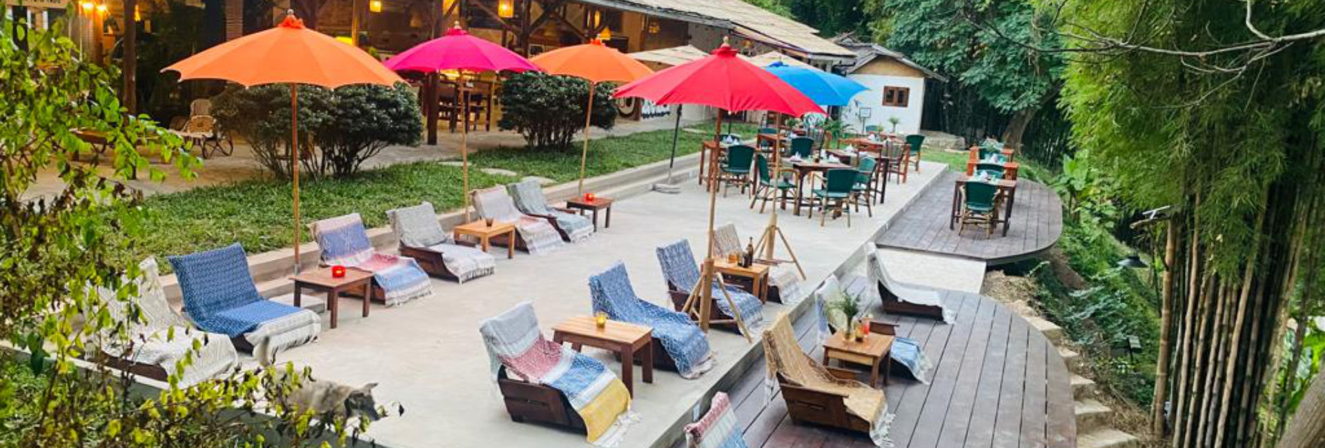 A restaurant in Luang Prabang with chairs and umbrellas on a wooden deck.
