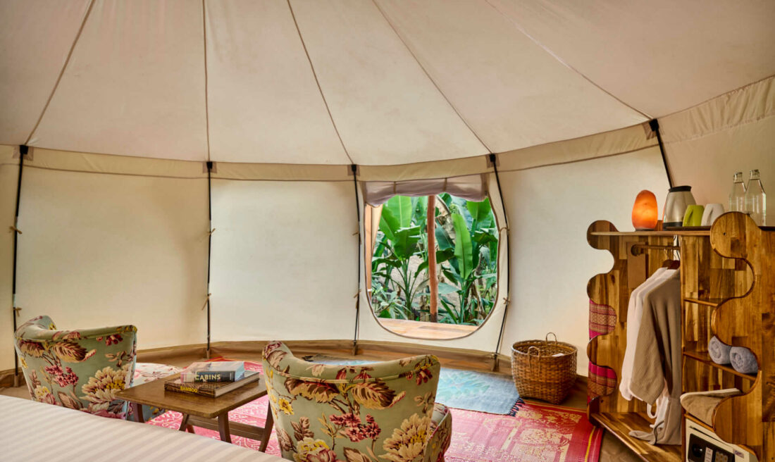 A teepee tent with a bed, chairs, and a window in Luang Prabang.