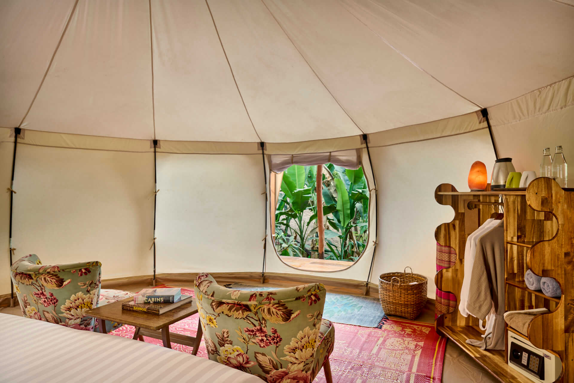A teepee tent with a bed, chairs, and a window in Luang Prabang.