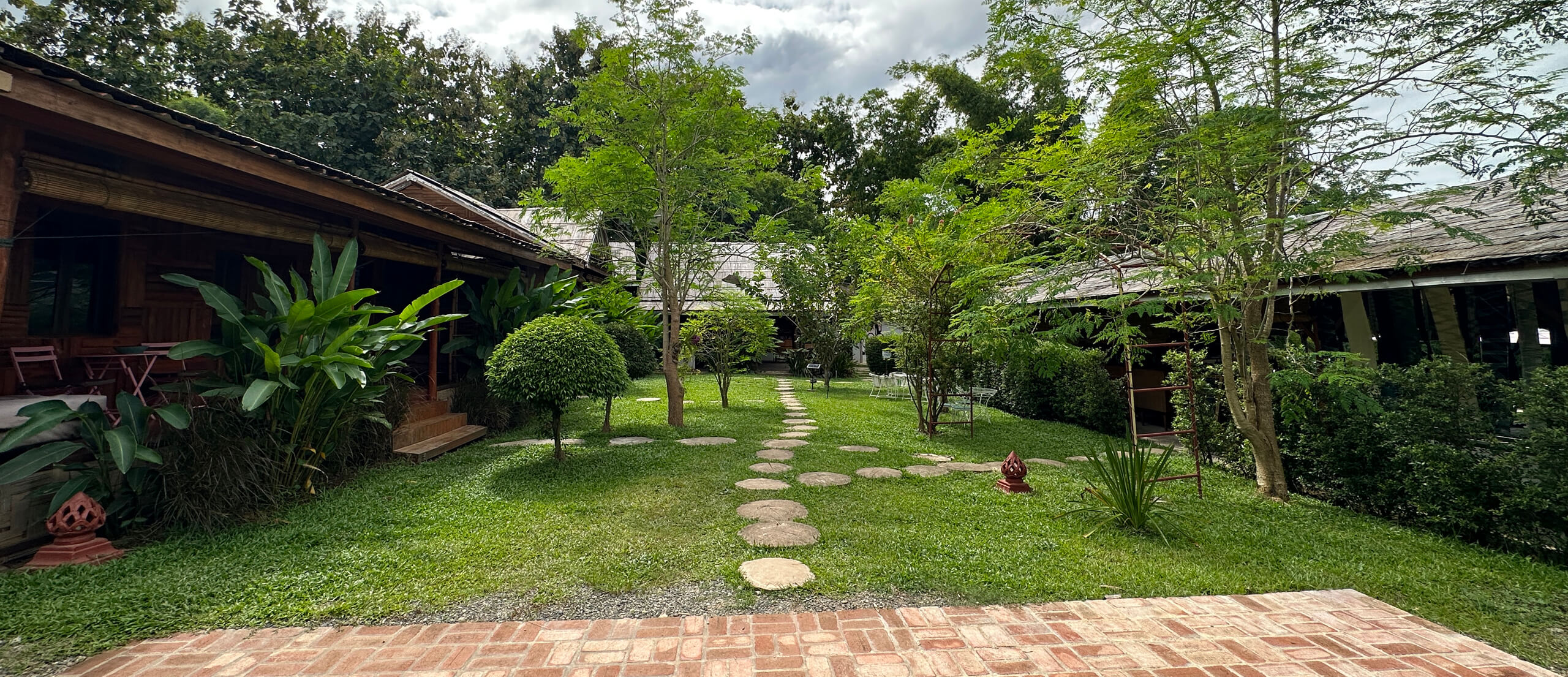 A Luang Prabang garden with a pathway leading to a house.