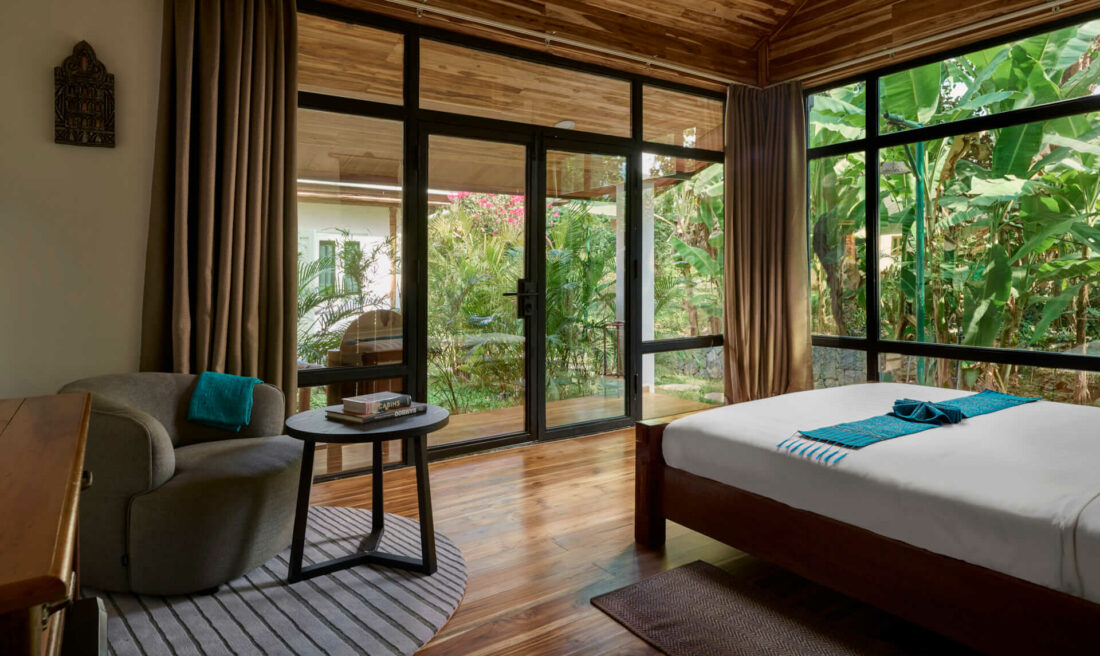 A luang prabang bedroom with a wooden floor and a view of the jungle.