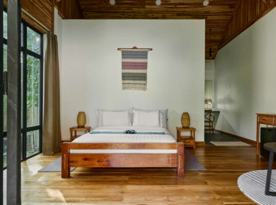A bedroom in Luang Prabang with wooden floors and a wooden bed.