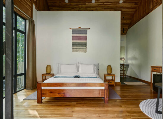 A bedroom in Luang Prabang with wooden floors and a wooden bed.