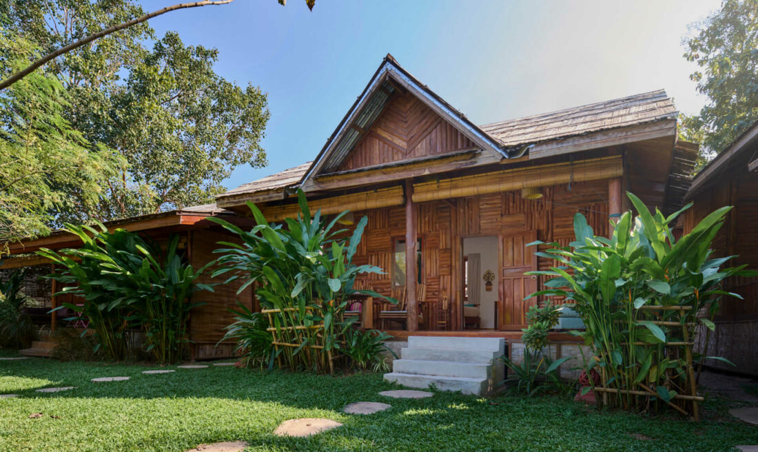 A luang prabang wooden house surrounded by lush greenery.
