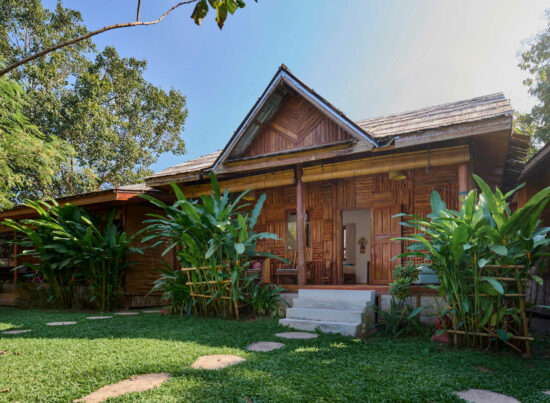 A luang prabang wooden house surrounded by lush greenery.