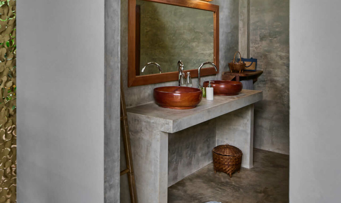 A luang prabang bathroom with two sinks and a wooden wall.