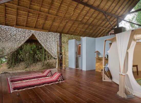 A luang prabang room with a wooden floor and a bed in it.