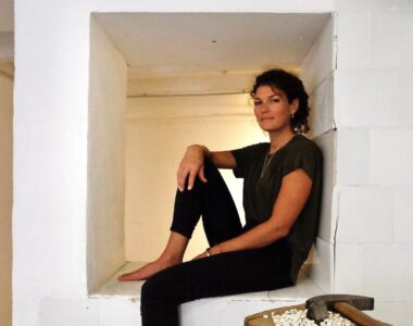 A woman sitting on a ledge in a Luang Prabang-inspired white room.