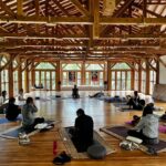 A group of people practicing yoga in a large wooden room in Luang Prabang.