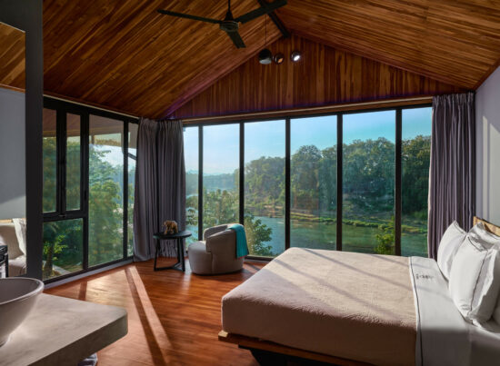 A Luang Prabang bedroom with a large window overlooking a river.