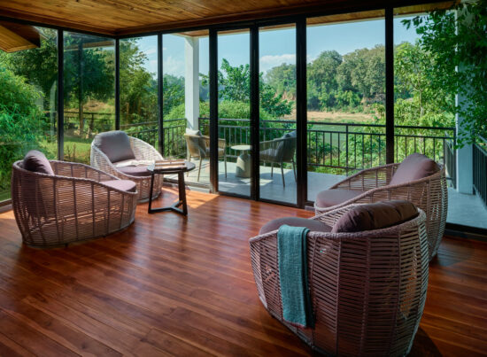 A screened in porch with wicker furniture and a breathtaking view of Luang Prabang.