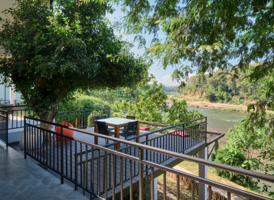 A Luang Prabang balcony overlooking a river and trees.