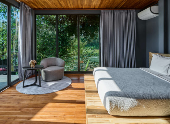 A luang prabang bedroom with a large bed and a view of the woods.