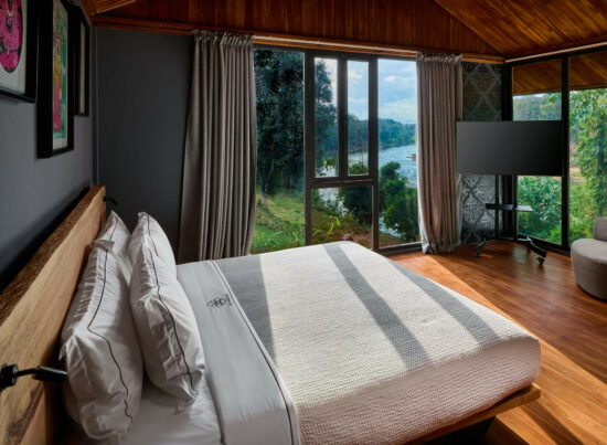 A bedroom in Luang Prabang with wooden floors and a view of a lake.
