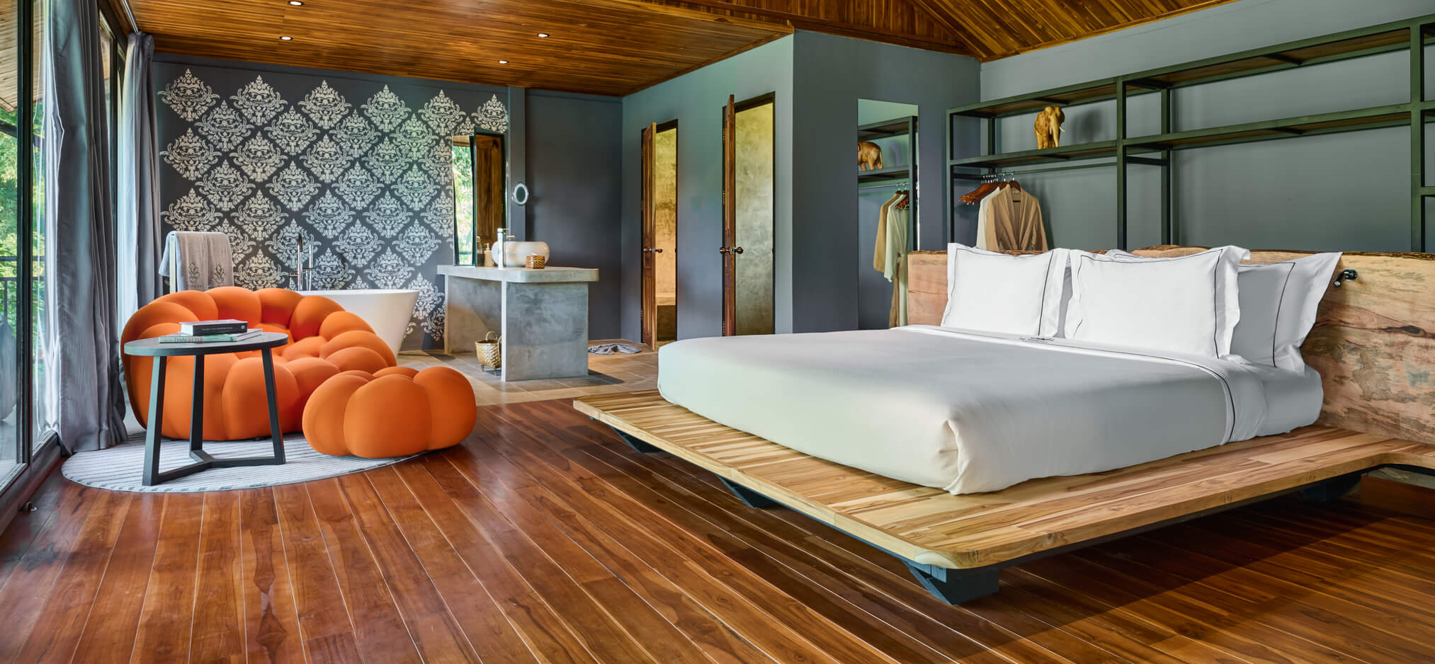 A luang prabang-inspired bedroom with wooden floors and a bed.