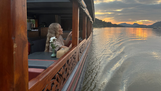 A woman sitting on a boat at sunset in Luang Prabang.